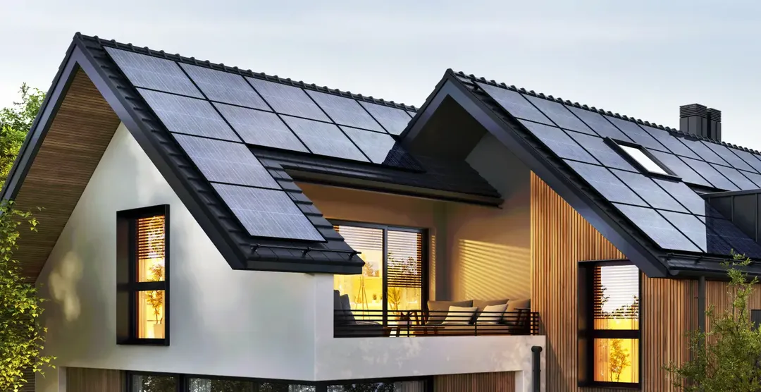 Haus mit dunklen Solarmodulen auf dem Dach.
